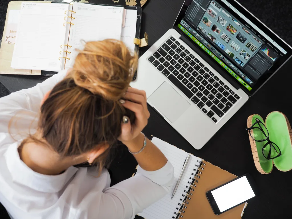 woman sitting in front of macbook, Turhat keskeytykset työssä heikentävät työn sujumista ja lisäävät aivokuormaa.
